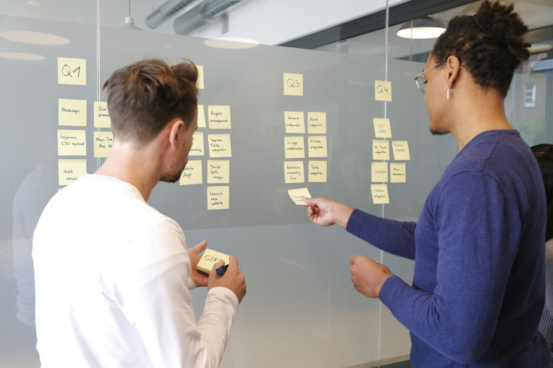 Two people planning with sticky notes on a glass wall